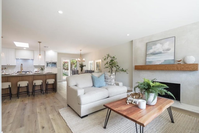 living room featuring a chandelier, light wood-type flooring, a fireplace, and recessed lighting