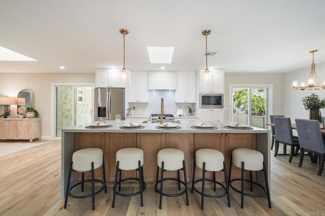 kitchen featuring visible vents, white cabinetry, light countertops, appliances with stainless steel finishes, and a large island