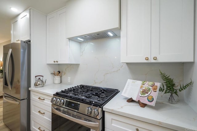 kitchen with stainless steel appliances, light stone counters, decorative backsplash, and white cabinets