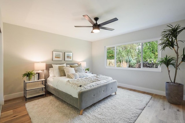 bedroom featuring ceiling fan, baseboards, and wood finished floors