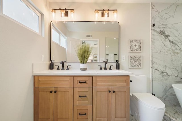 bathroom with double vanity, a freestanding bath, visible vents, and a sink