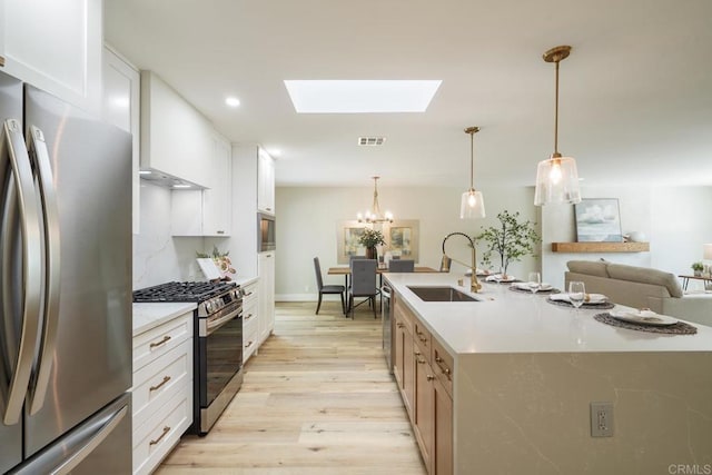 kitchen with visible vents, stainless steel appliances, light countertops, light wood-style floors, and a sink