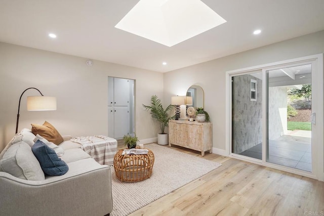 living room featuring light wood-type flooring, a skylight, baseboards, and recessed lighting