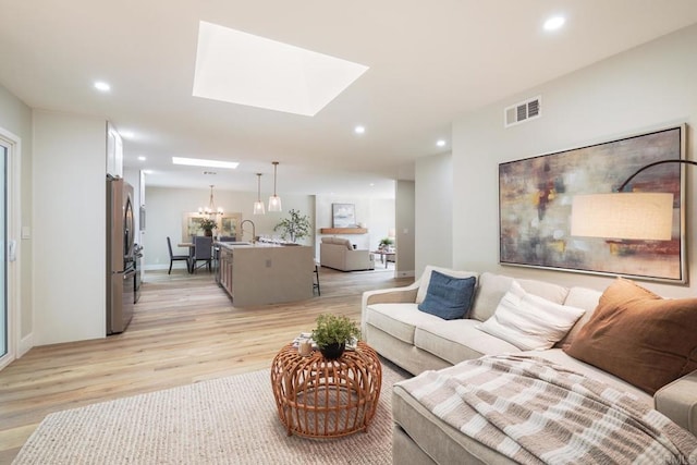 living area with a skylight, light wood-style flooring, visible vents, and recessed lighting