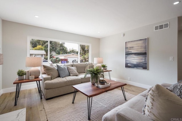 living room featuring light wood finished floors, baseboards, and visible vents