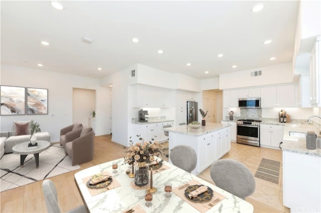 dining area with light wood-style floors, visible vents, and recessed lighting