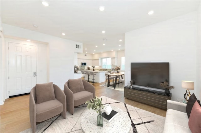 living room with light wood-type flooring, visible vents, and recessed lighting