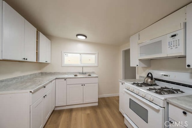 kitchen with white appliances, white cabinetry, light countertops, and a sink