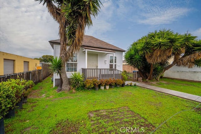 view of front of house with stucco siding, a porch, a front lawn, and fence