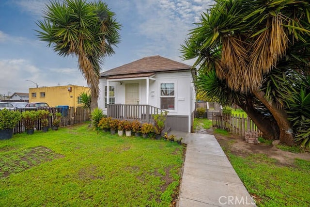 bungalow-style house featuring stucco siding, a front lawn, and fence