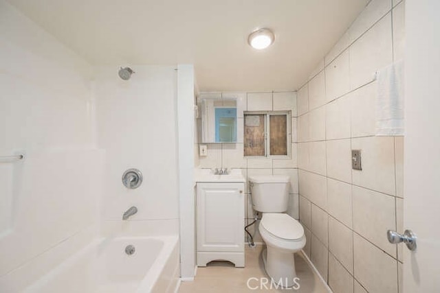 bathroom featuring tile walls, vanity, toilet, and shower / tub combination