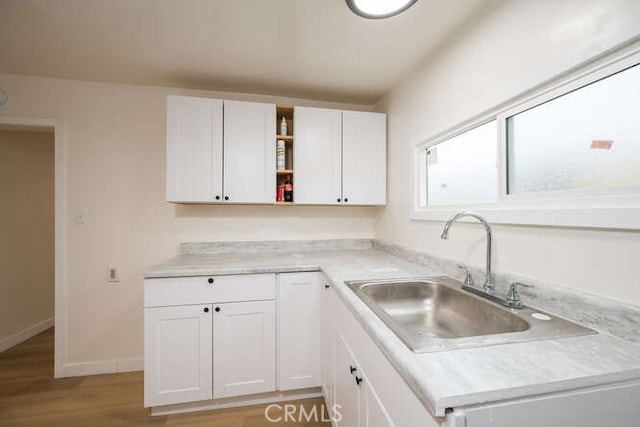 kitchen featuring white cabinetry, open shelves, light wood-style floors, and a sink