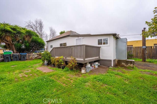 rear view of property featuring a yard, a deck, and fence