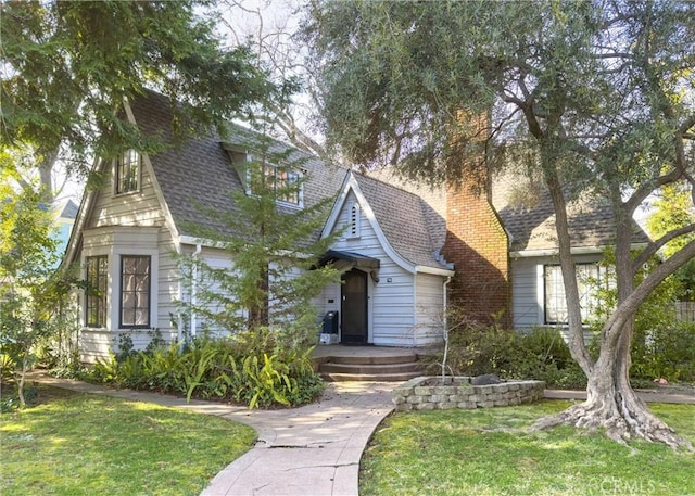 view of front of home with roof with shingles and a front lawn