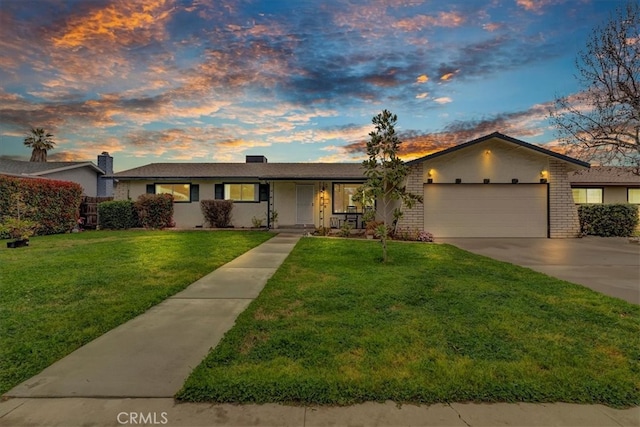 single story home with a garage, brick siding, a lawn, and driveway