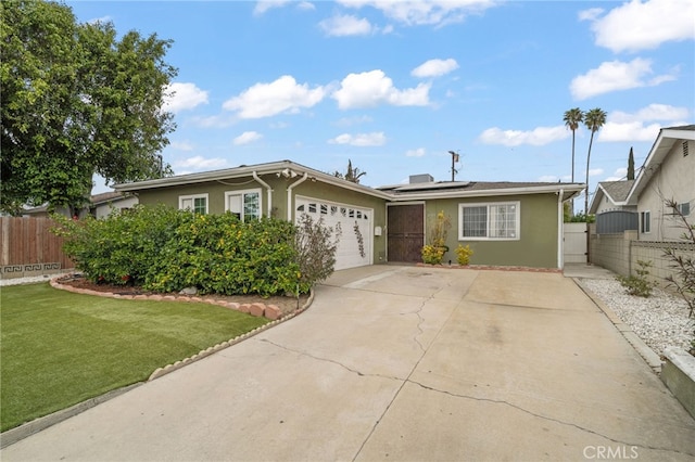 single story home featuring concrete driveway, solar panels, a gate, fence, and stucco siding