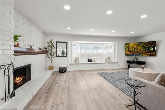 living area featuring a brick fireplace, wood finished floors, and recessed lighting