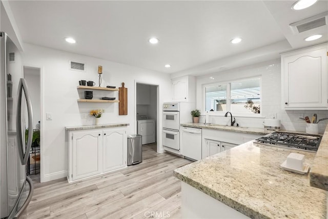 kitchen with stainless steel appliances, washer / clothes dryer, a sink, and light stone countertops