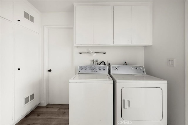 laundry room featuring visible vents, light wood-type flooring, washing machine and dryer, and cabinet space