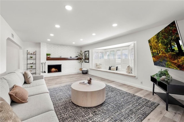 living area featuring recessed lighting, a fireplace, baseboards, and wood finished floors