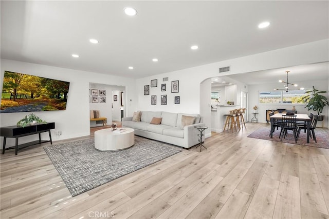 living room with arched walkways, recessed lighting, visible vents, baseboards, and light wood finished floors