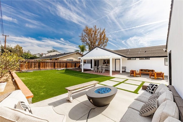 rear view of property featuring a lawn, a patio area, an outdoor living space with a fire pit, and a fenced backyard