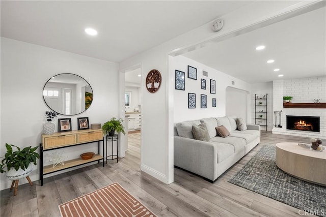 living room with a brick fireplace, baseboards, wood finished floors, and recessed lighting