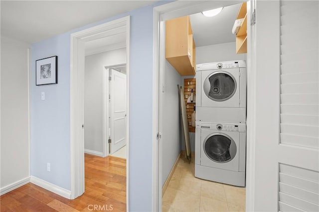 laundry area featuring laundry area, baseboards, light wood-style floors, and stacked washer and clothes dryer