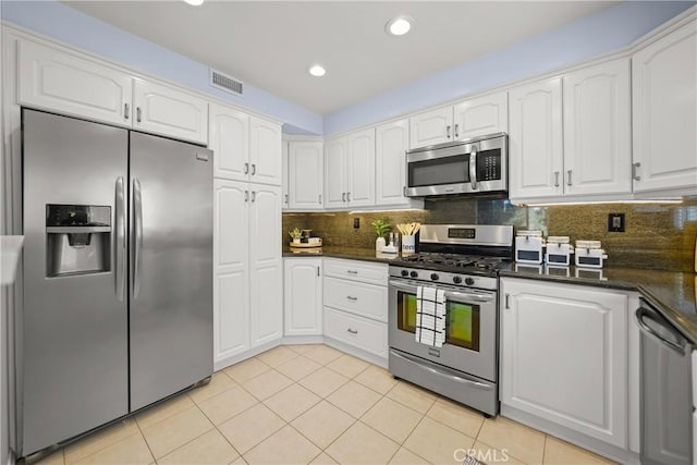 kitchen with light tile patterned floors, dark countertops, visible vents, appliances with stainless steel finishes, and white cabinets