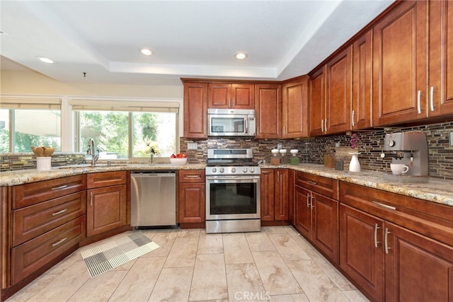 kitchen with a healthy amount of sunlight, stainless steel appliances, decorative backsplash, and a raised ceiling