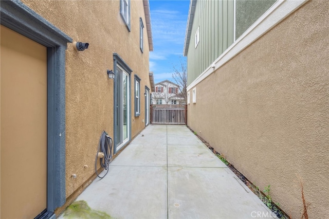 view of property exterior featuring a patio, fence, and stucco siding