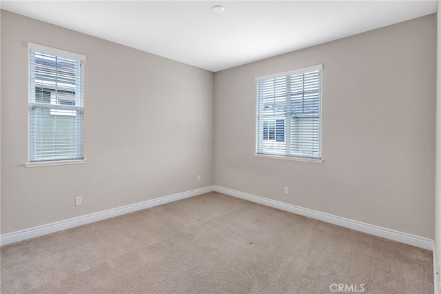 empty room featuring carpet and baseboards