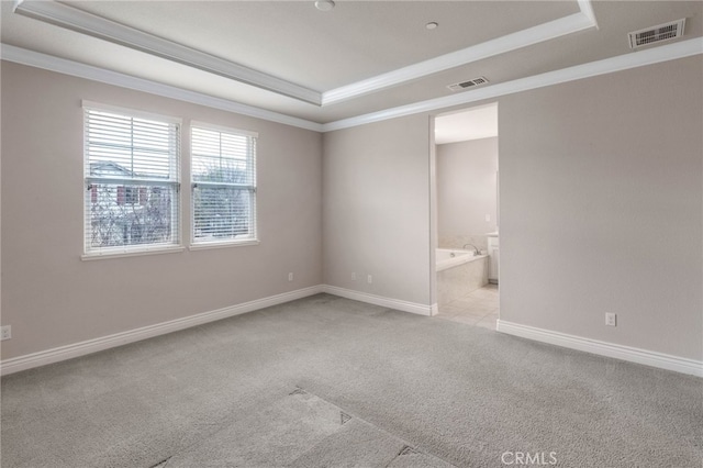 carpeted spare room featuring a raised ceiling, visible vents, and crown molding