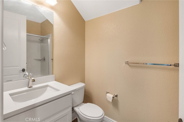 bathroom with toilet, a stall shower, a textured wall, and vanity