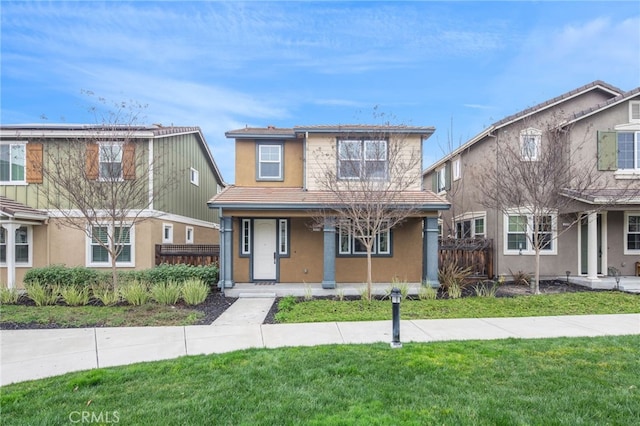 view of front of house featuring covered porch, a front yard, fence, and stucco siding