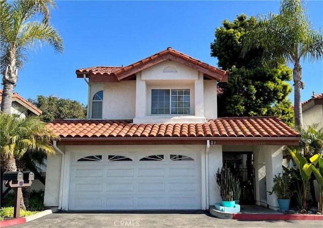 mediterranean / spanish house featuring driveway, a tile roof, and stucco siding