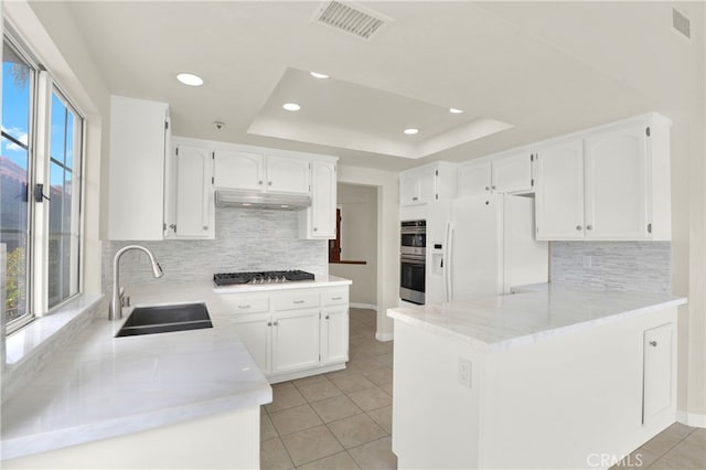 kitchen with decorative backsplash, light tile patterned floors, appliances with stainless steel finishes, a sink, and a peninsula