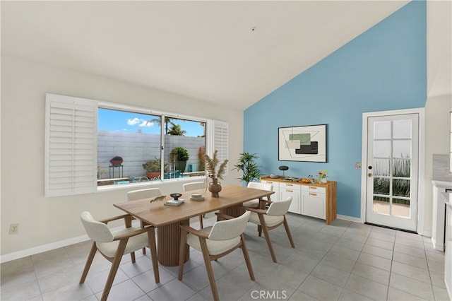 dining area with light tile patterned flooring, high vaulted ceiling, and baseboards