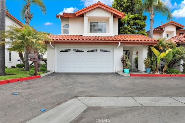 mediterranean / spanish-style home featuring driveway, stucco siding, and a tiled roof