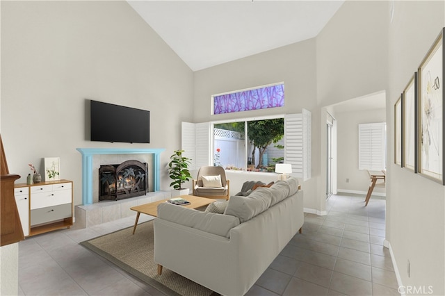 tiled living area with high vaulted ceiling, a tiled fireplace, and baseboards
