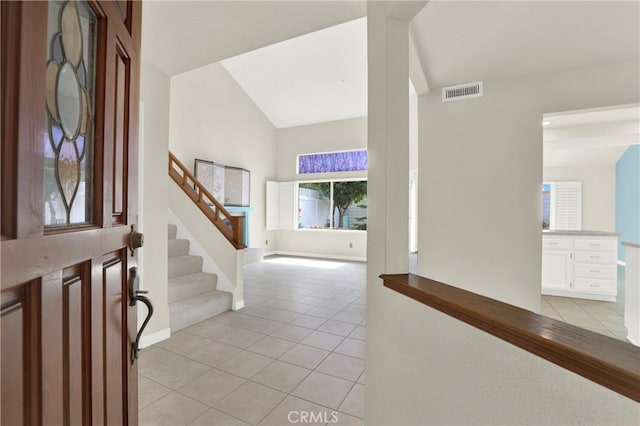 entryway with light tile patterned floors, stairs, visible vents, vaulted ceiling, and baseboards
