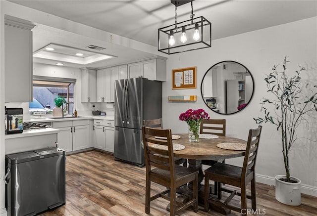 dining area featuring a tray ceiling, dark wood-style flooring, visible vents, and recessed lighting