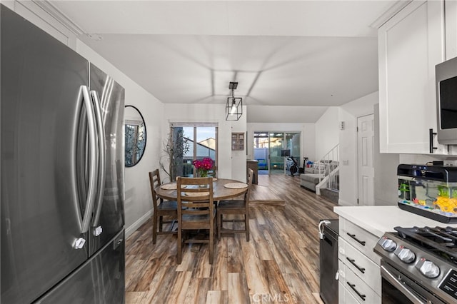 kitchen with light countertops, appliances with stainless steel finishes, white cabinets, wood finished floors, and baseboards