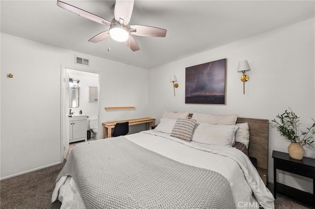 carpeted bedroom featuring a ceiling fan, ensuite bath, visible vents, and baseboards