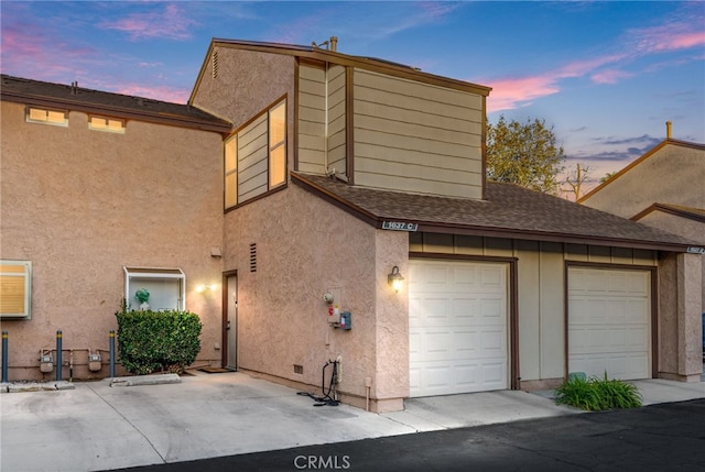 property exterior at dusk featuring a shingled roof and stucco siding