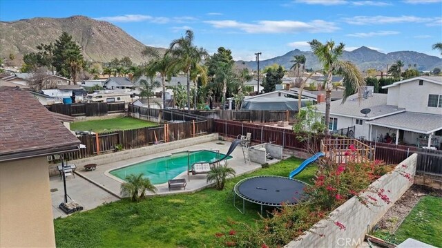 view of swimming pool with a fenced in pool, a residential view, a fenced backyard, a mountain view, and a patio