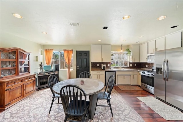 kitchen with visible vents, a sink, wood finished floors, appliances with stainless steel finishes, and decorative backsplash