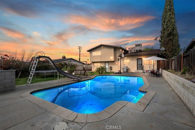 view of swimming pool featuring a patio area, a fenced in pool, fence private yard, and a water slide