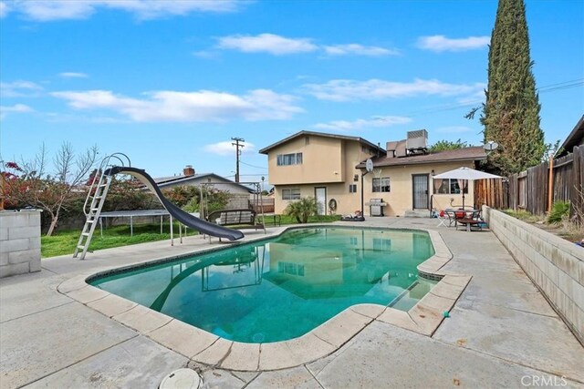 view of swimming pool with central AC, a fenced backyard, a water slide, a fenced in pool, and a patio area