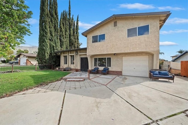 view of front facade with a front yard, fence, driveway, stucco siding, and a garage